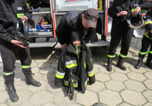 Chłopiec przymierza odzież strażaka.